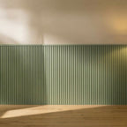 Four NU Wall Elegance Apex paintable wall panels with textured surface, stacked and leaning against a plain wall.